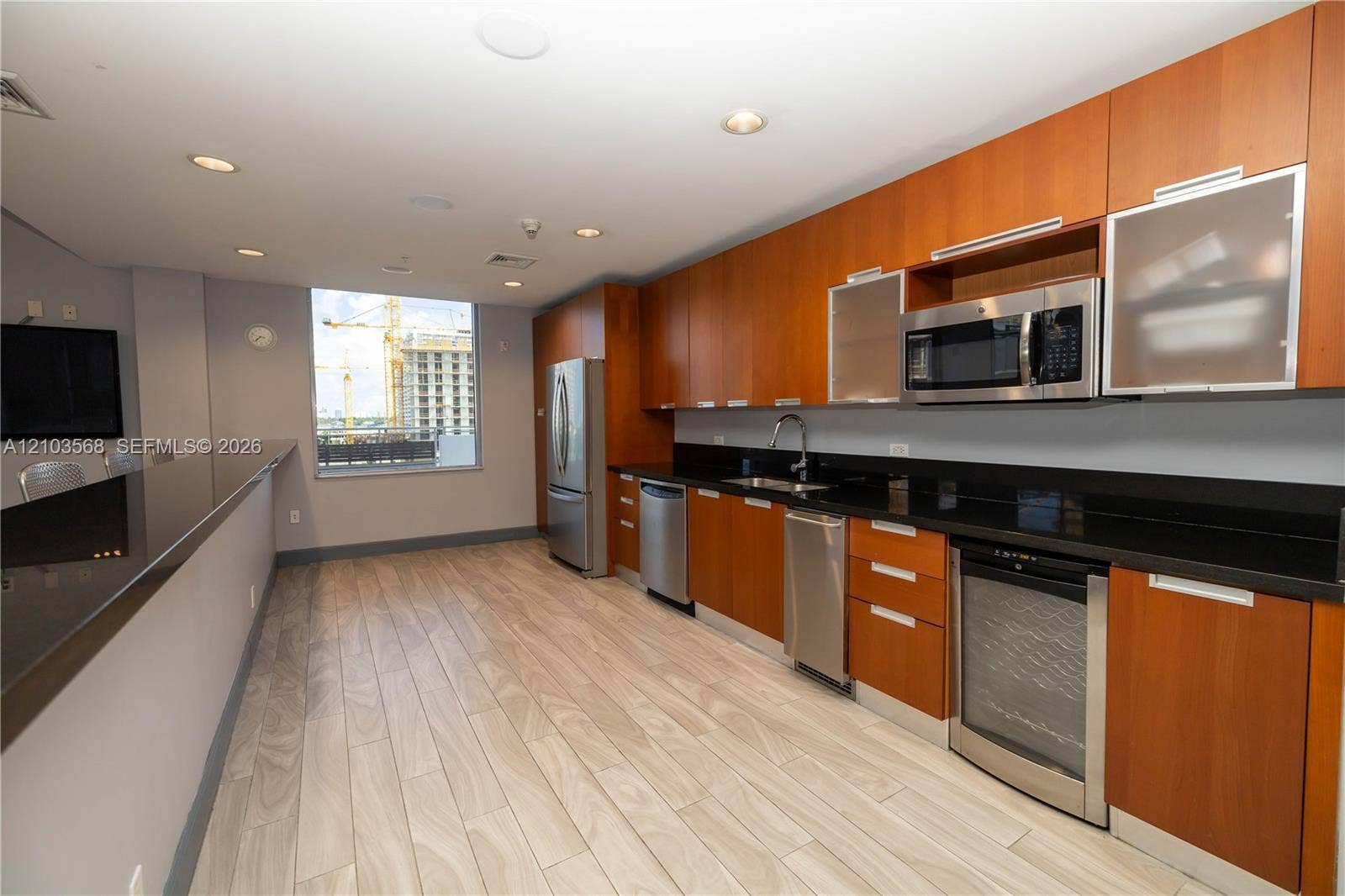7901 Hispanola Avenue, #801, North Bay Village, FL 33141 Kitchen featuring flat-panel wood cabinetry, dark solid-surface countertops, built-in stainless steel appliances, a wine refrigerator, and wood-finish tile flooring