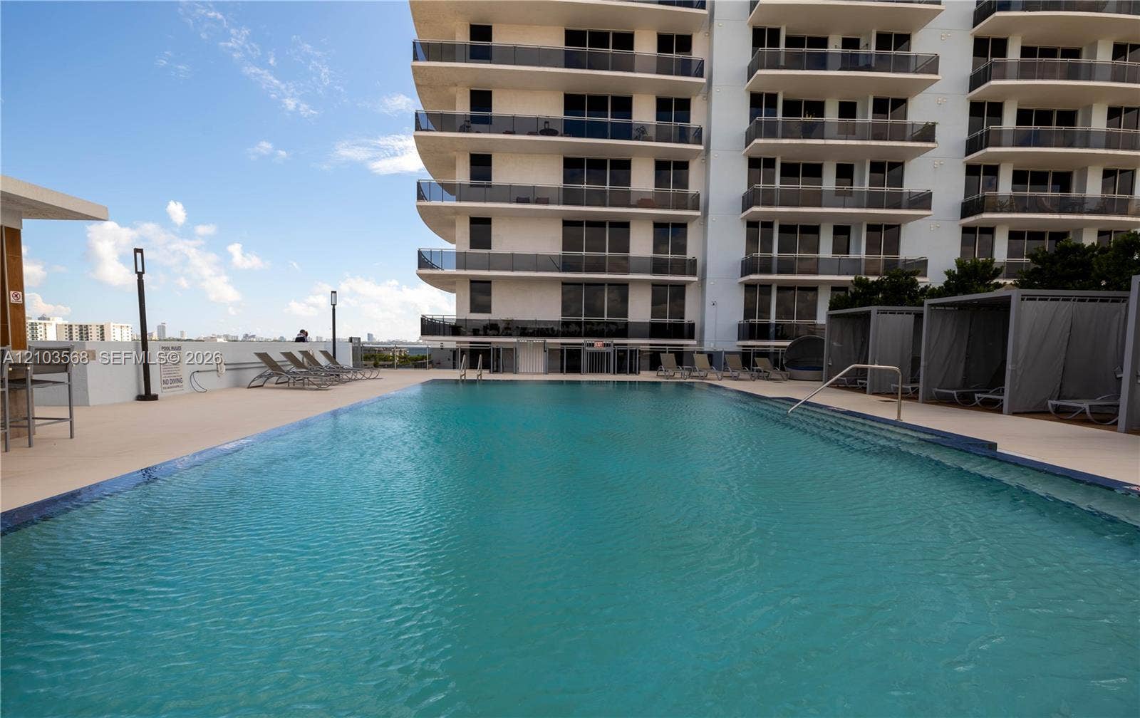 7901 Hispanola Avenue, #801, North Bay Village, FL 33141 Swimming pool featuring a tiled waterline, metal handrails, and a surrounding deck with built-in poolside cabanas