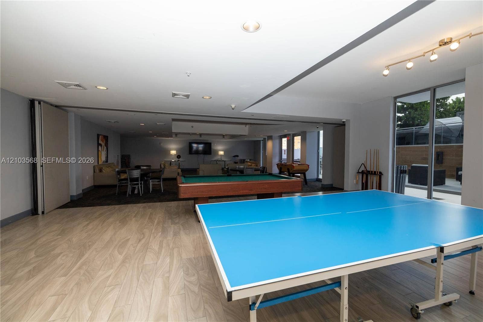 7901 Hispanola Avenue, #801, North Bay Village, FL 33141 Open-concept recreational space featuring wood-finish flooring, recessed lighting, multi-directional track lighting, and floor-to-ceiling glass sliding doors