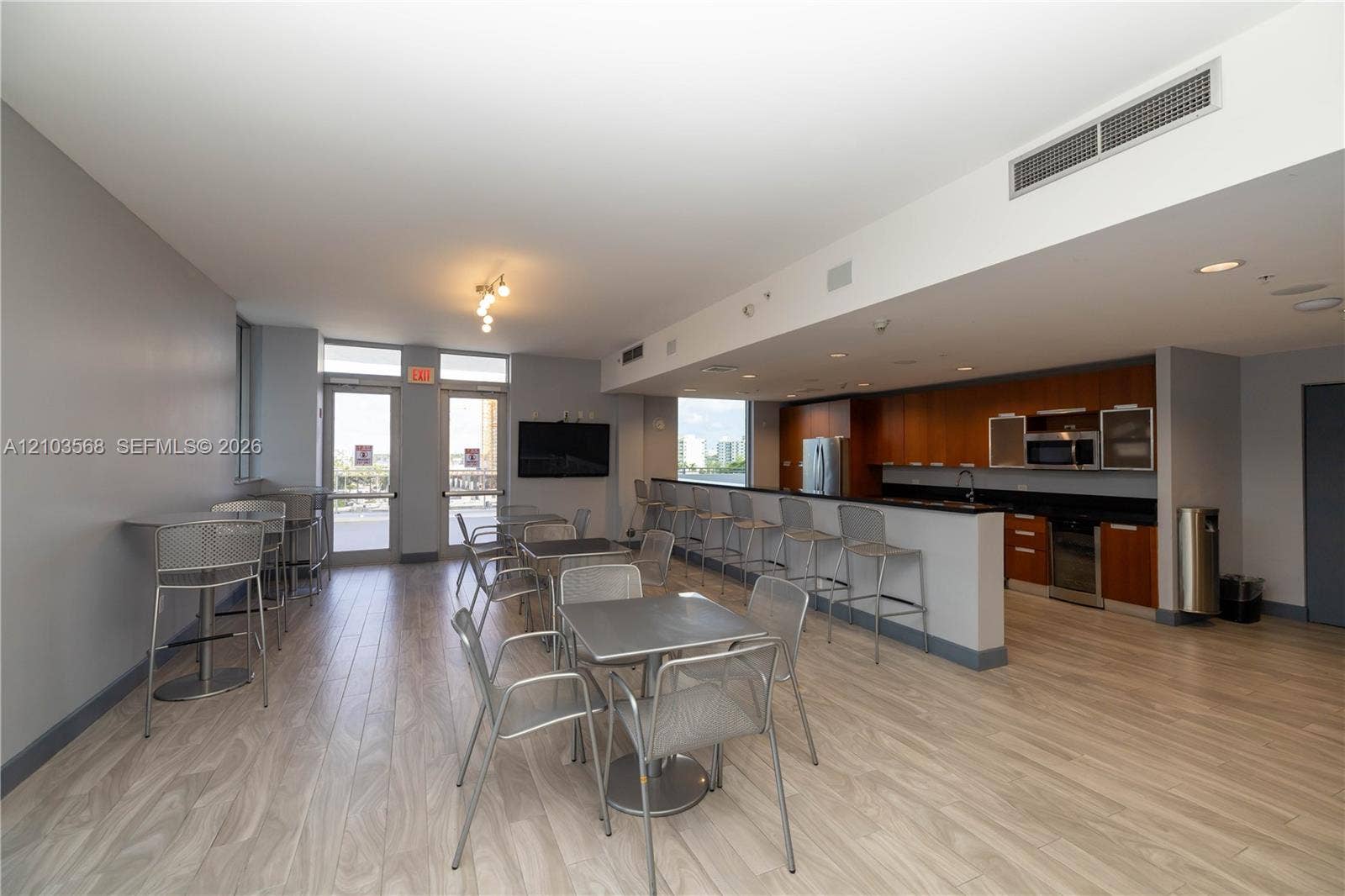 7901 Hispanola Avenue, #801, North Bay Village, FL 33141 Kitchen area featuring wood-finish cabinetry, dark solid-surface countertops, and stainless steel appliances, complemented by wood-finish flooring and recessed lighting