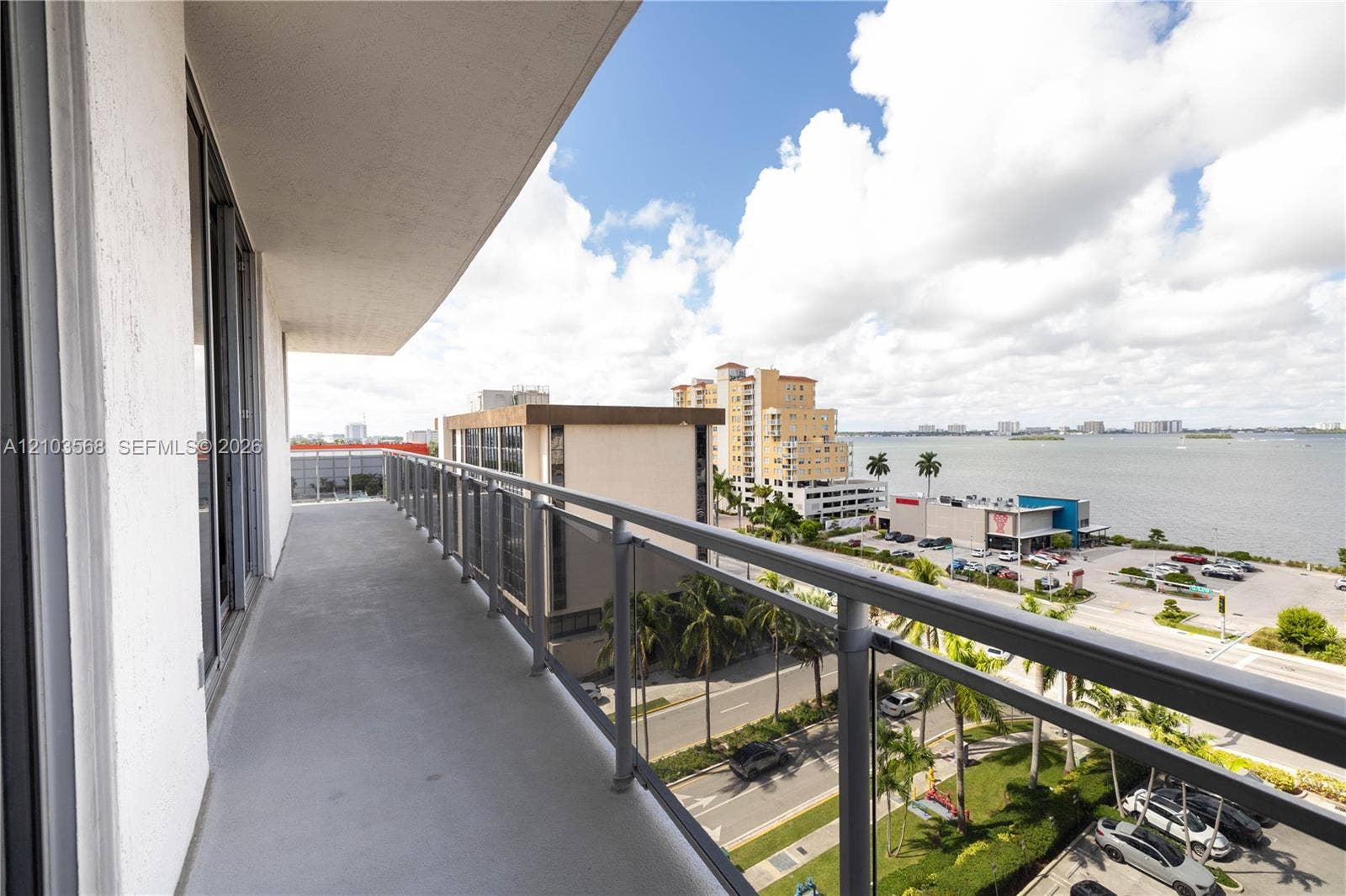 7901 Hispanola Avenue, #801, North Bay Village, FL 33141 Covered balcony featuring concrete flooring and a metal railing with glass panels, showcasing a water backdrop