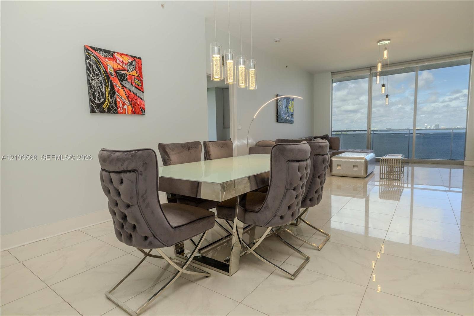 7901 Hispanola Avenue, #801, North Bay Village, FL 33141 Open-concept living space with polished stone flooring, floor-to-ceiling glass paneling, and multi-pendant lighting fixtures