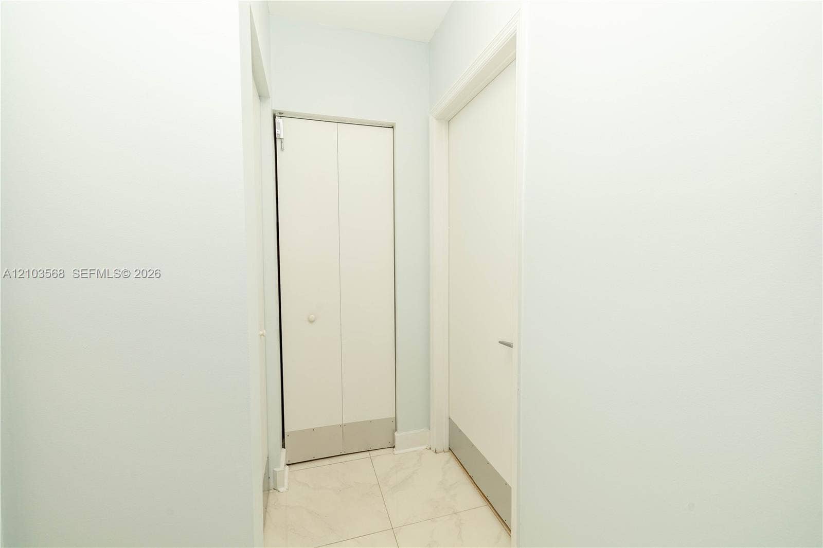7901 Hispanola Avenue, #801, North Bay Village, FL 33141 White bifold closet doors, interior door with a minimalist handle, and light-toned tile flooring