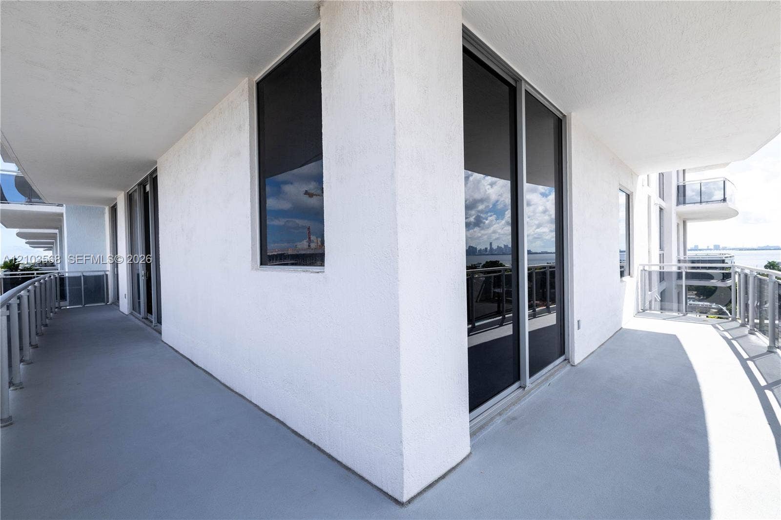 7901 Hispanola Avenue, #801, North Bay Village, FL 33141 Wrap-around balcony featuring smooth concrete flooring, stucco exterior walls, metal railings, and floor-to-ceiling sliding glass doors