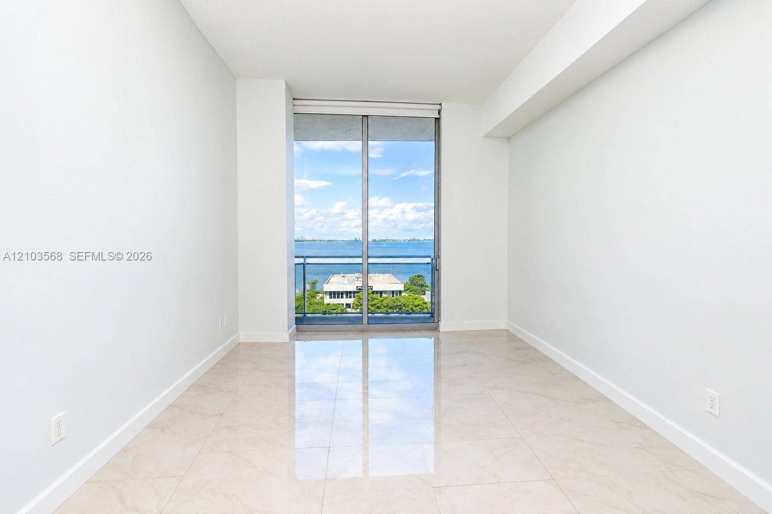 7901 Hispanola Avenue, #801, North Bay Village, FL 33141 Neutral-toned tile flooring, floor-to-ceiling glass sliding door, and balcony access with water surroundings