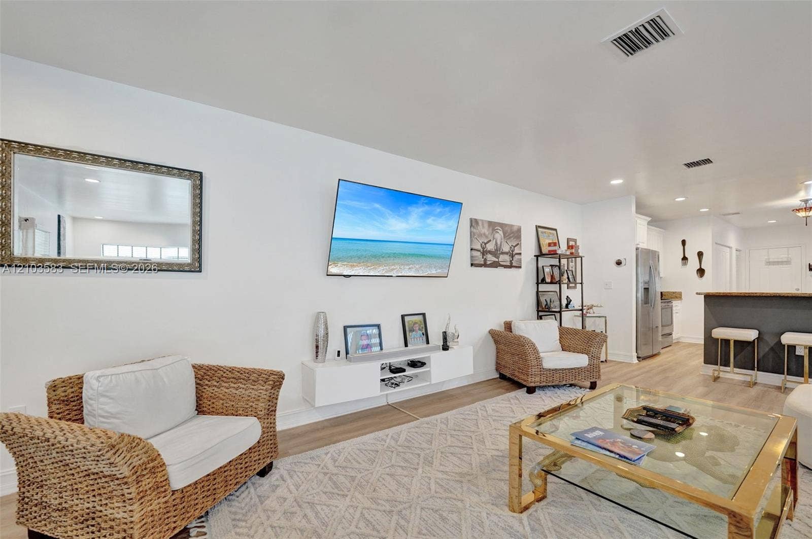 Open-concept interior featuring light-toned wood-finish flooring, recessed lighting, and a white floating media console