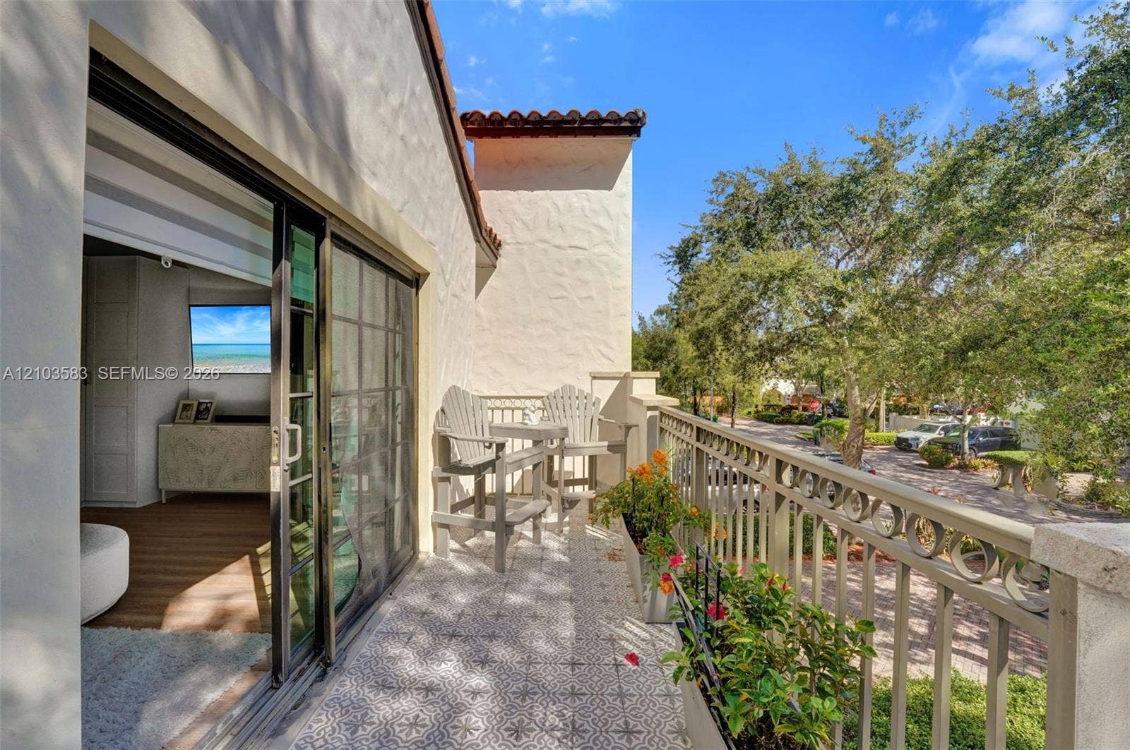 Stucco exterior balcony featuring patterned tile flooring, a metal railing, and sliding glass door access