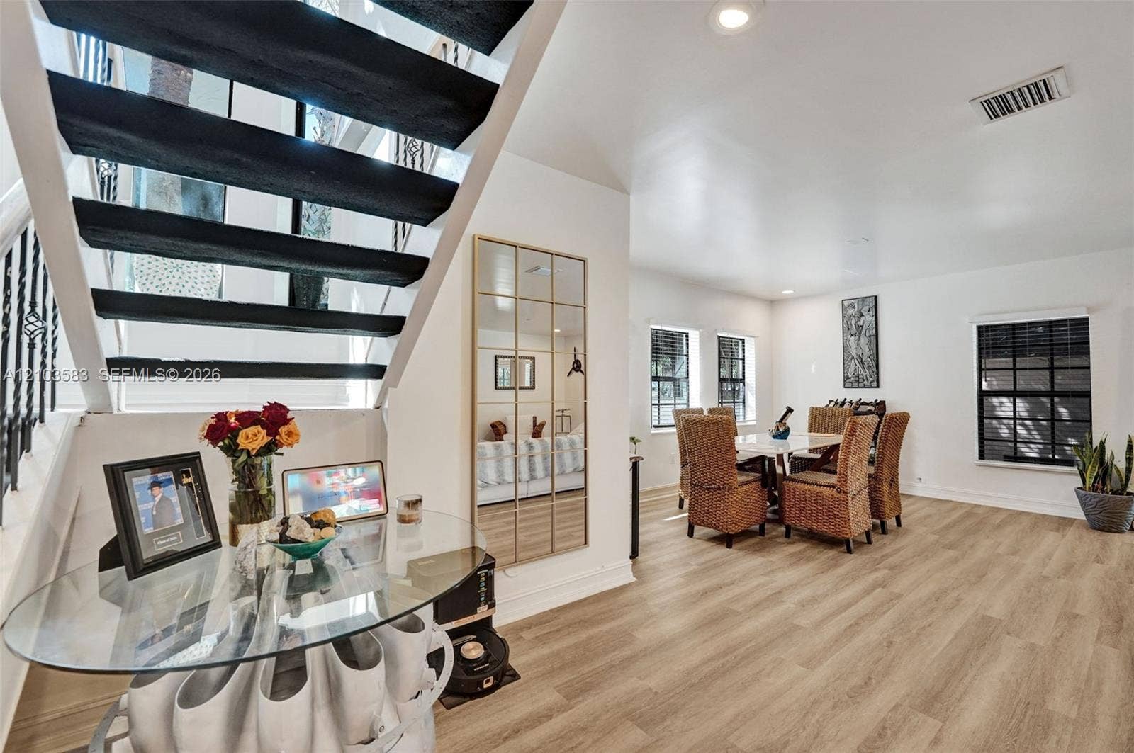 Staircase featuring black open-tread risers and decorative iron railing, wood-finish flooring, recessed lighting, and grid-pane windows