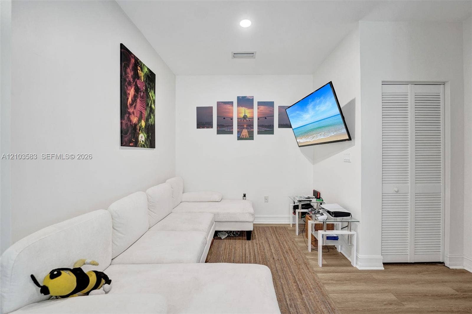 Neutral interior featuring wood-finish flooring, recessed ceiling lighting, and a closet with white louvered doors