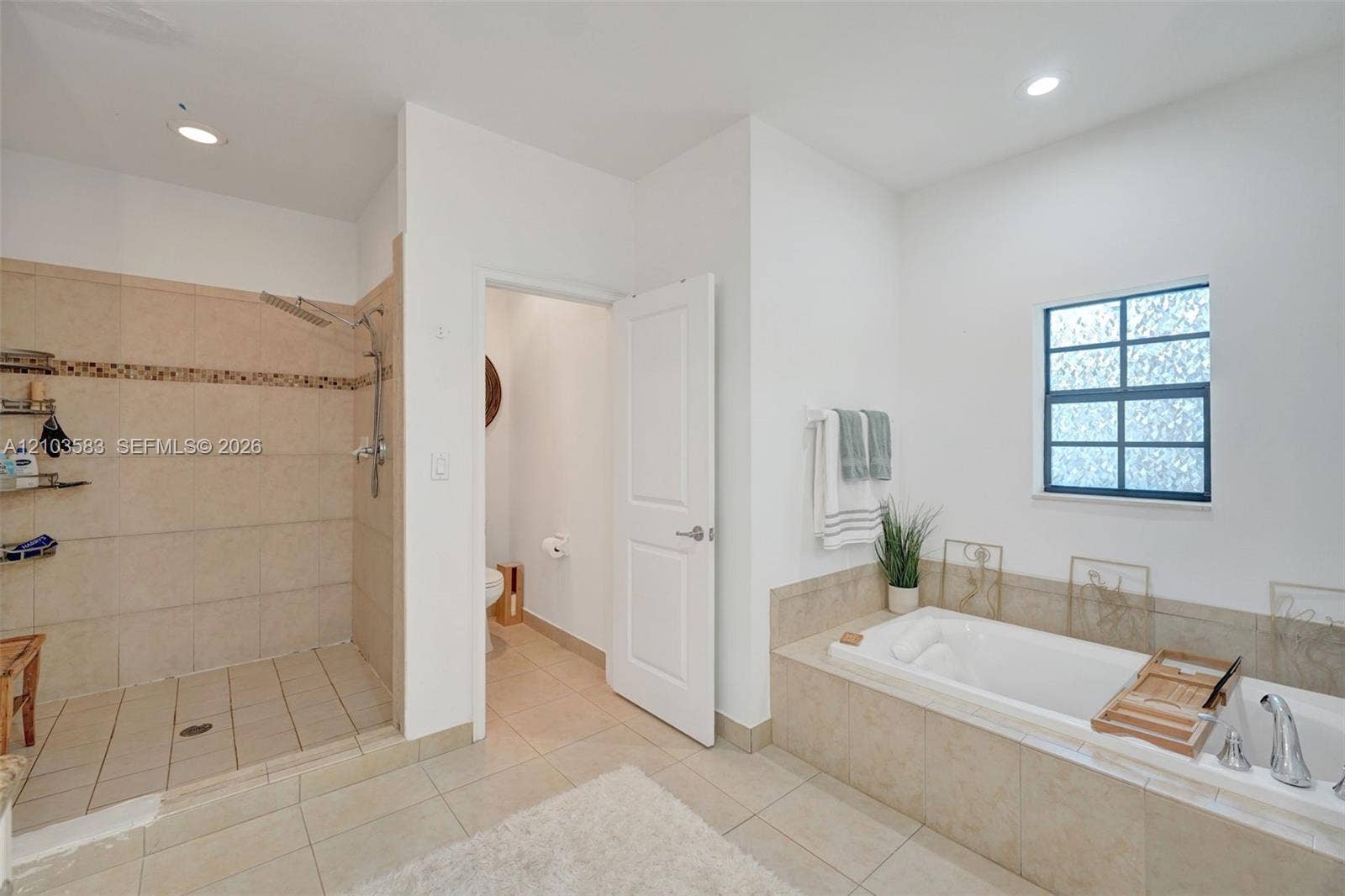 Bathroom featuring a tile-surround walk-in shower with a mosaic accent border, a built-in soaking tub with tile surround, recessed lighting, and large-format tile flooring