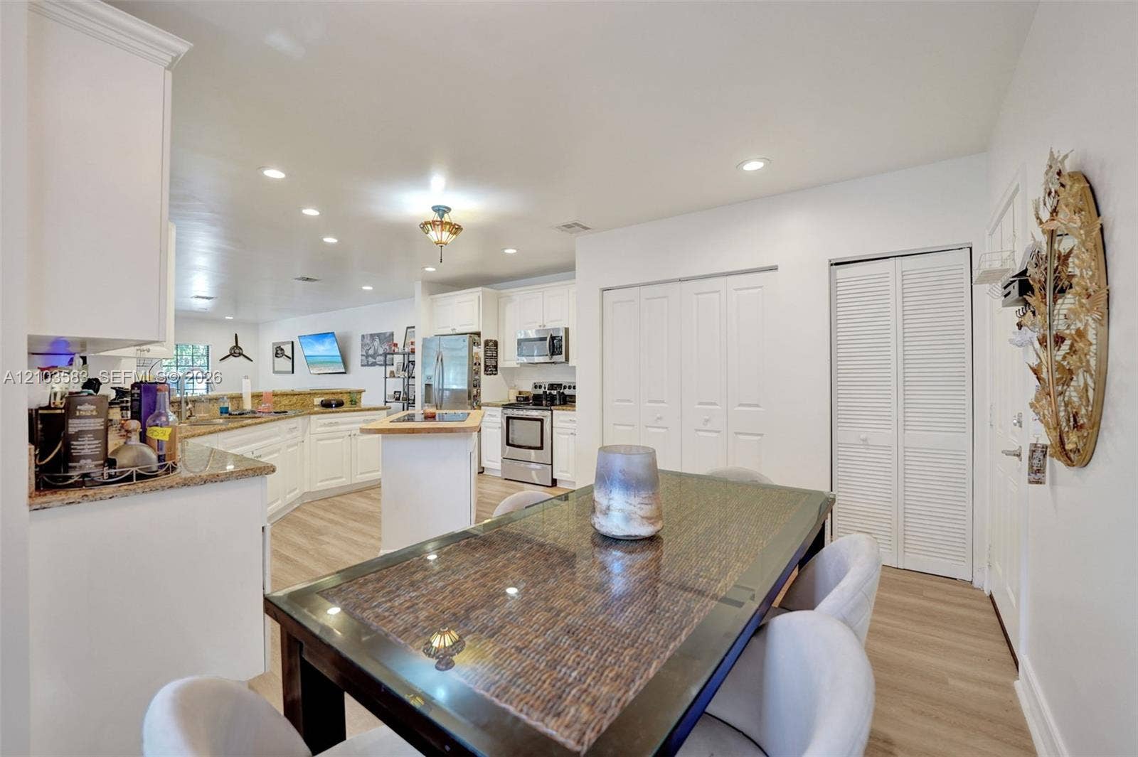 Kitchen featuring white cabinetry, stone countertops, stainless steel appliances, wood-finish flooring, and recessed lighting