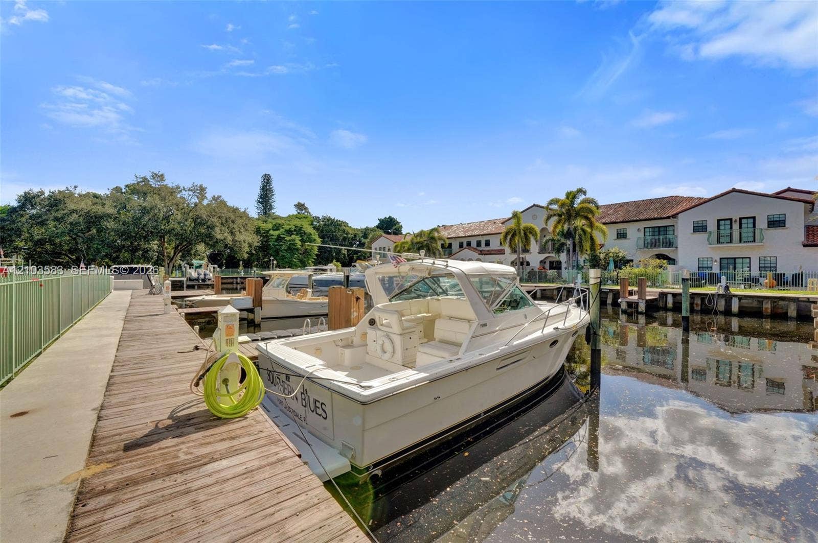 Private wooden dock featuring a concrete walkway, utility pedestal, and direct bulkhead access to the waterway