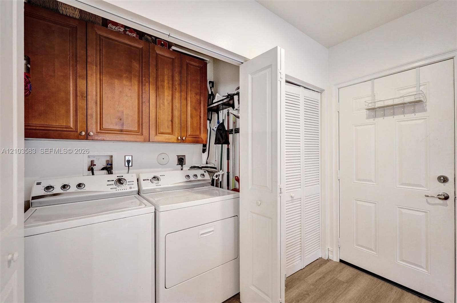 Laundry room featuring wood-finish cabinetry, louvered closet doors, and wood-finish flooring