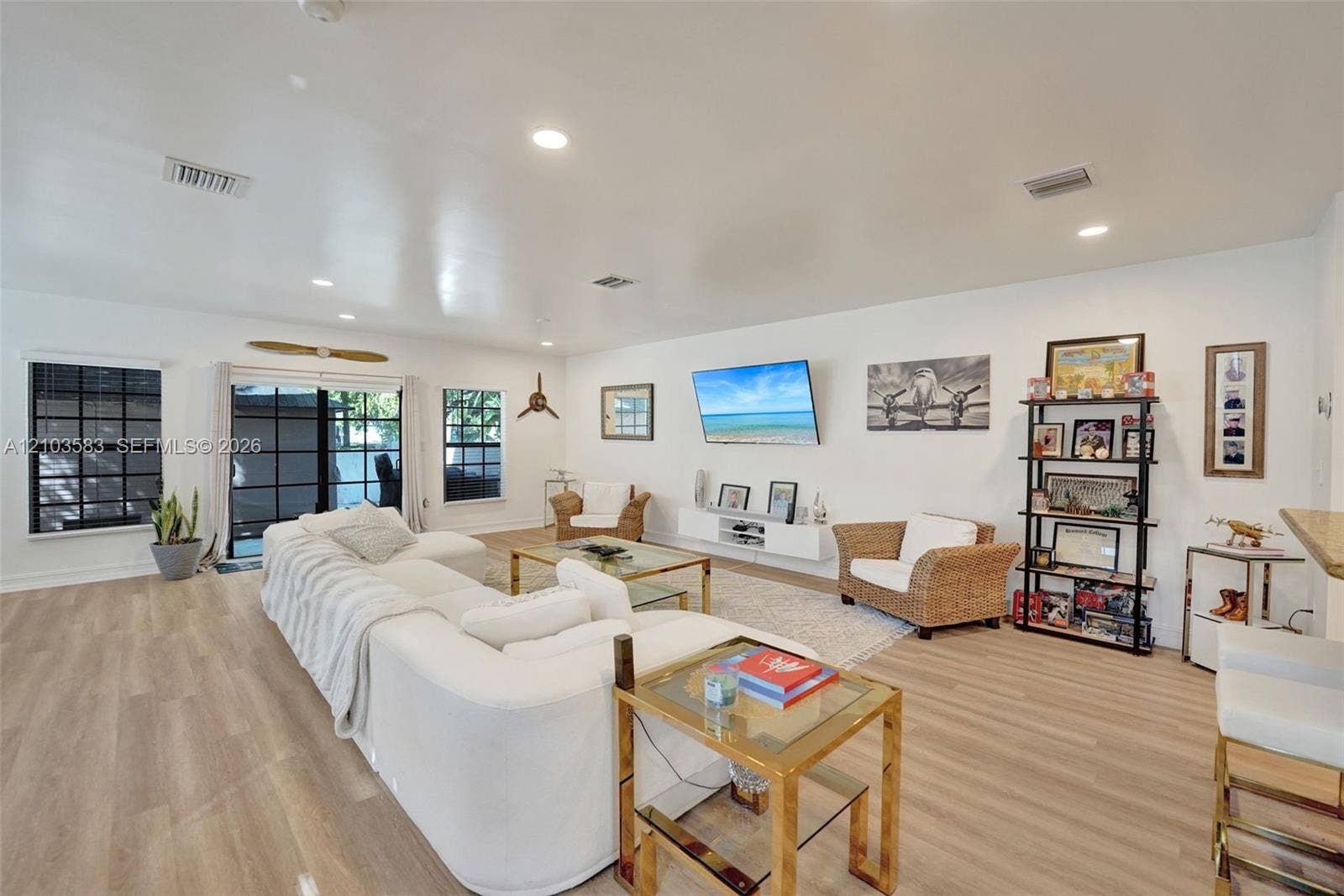 Open-concept living space featuring wood-finish flooring, recessed lighting, expansive glass sliding doors, and neutral wall tones