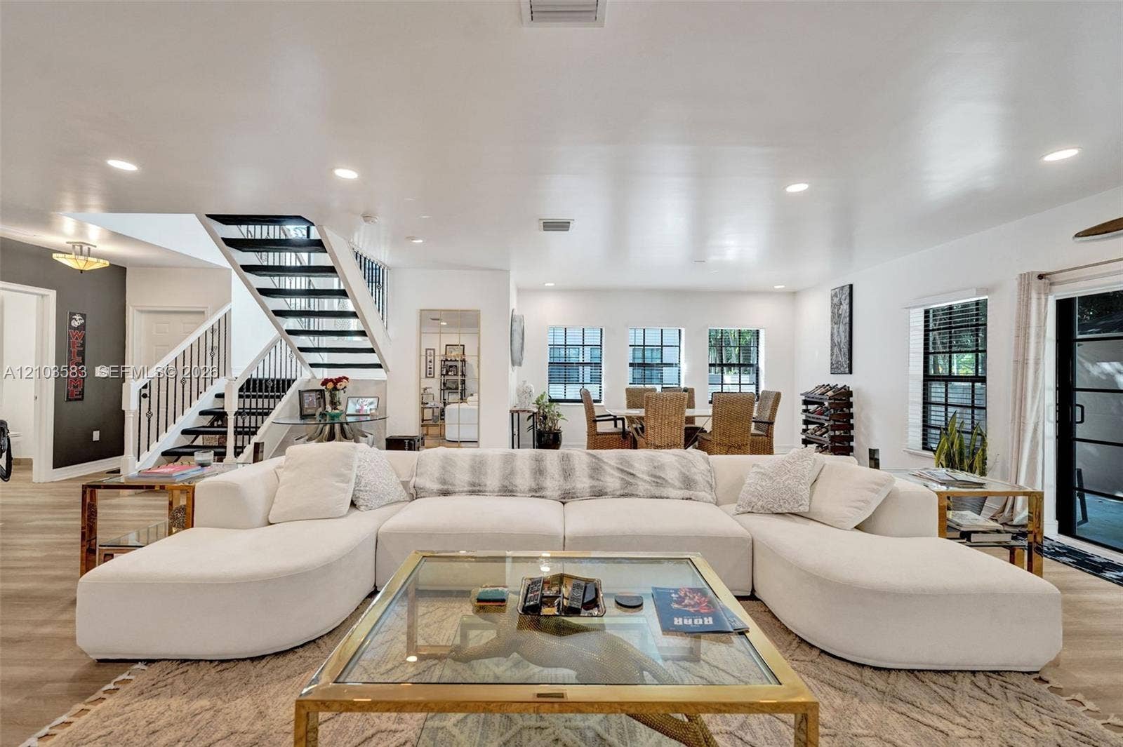 Open-concept interior featuring wood-finish flooring, recessed lighting, and a staircase with a black metal railing