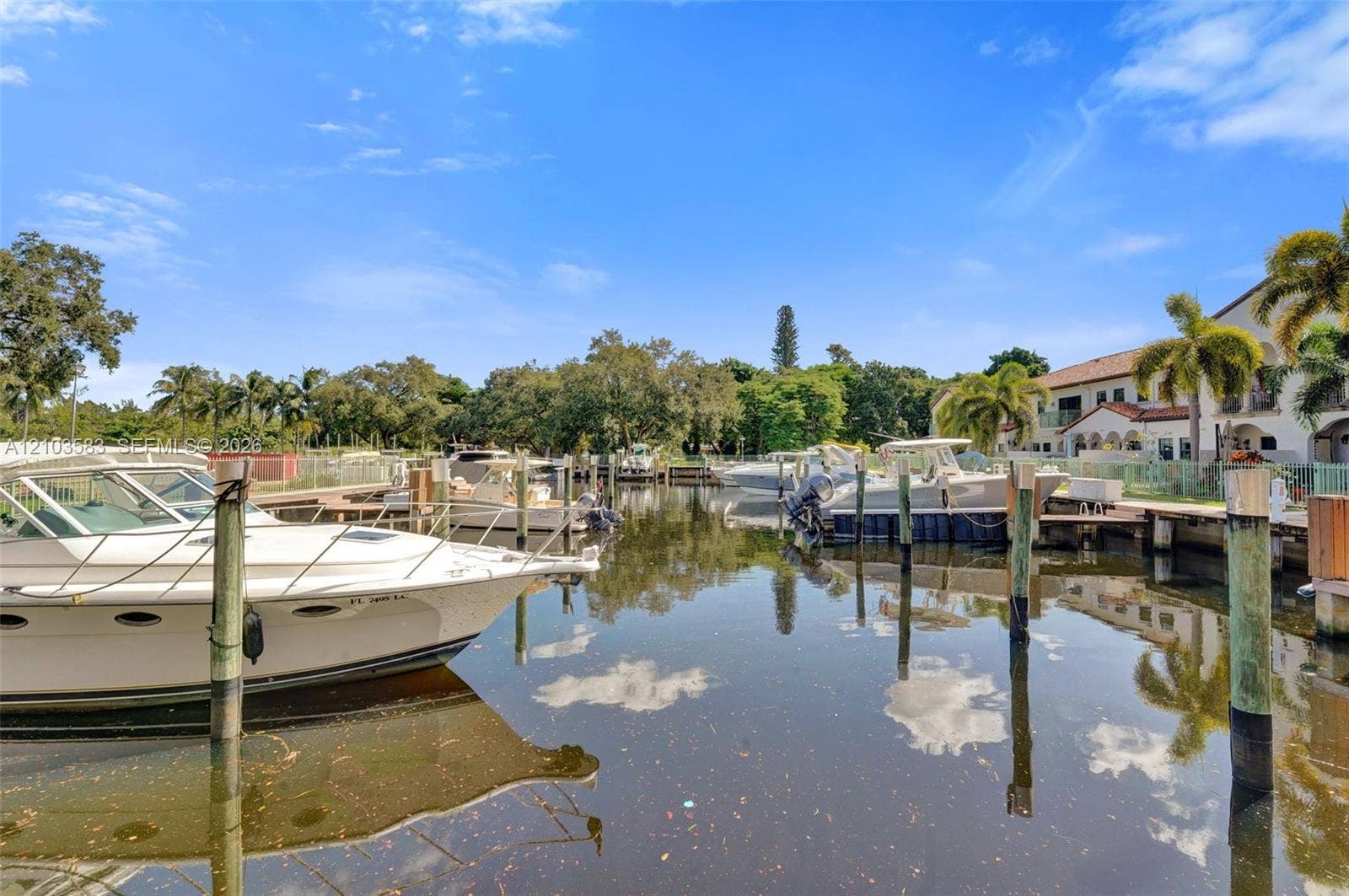 Waterfront property featuring a private boat slip, dock pilings, and mature palm trees