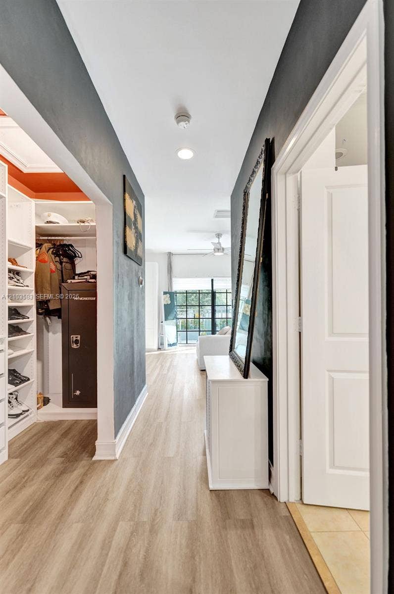 Hallway featuring wood-finish flooring, recessed lighting, and a walk-in closet with built-in shelving
