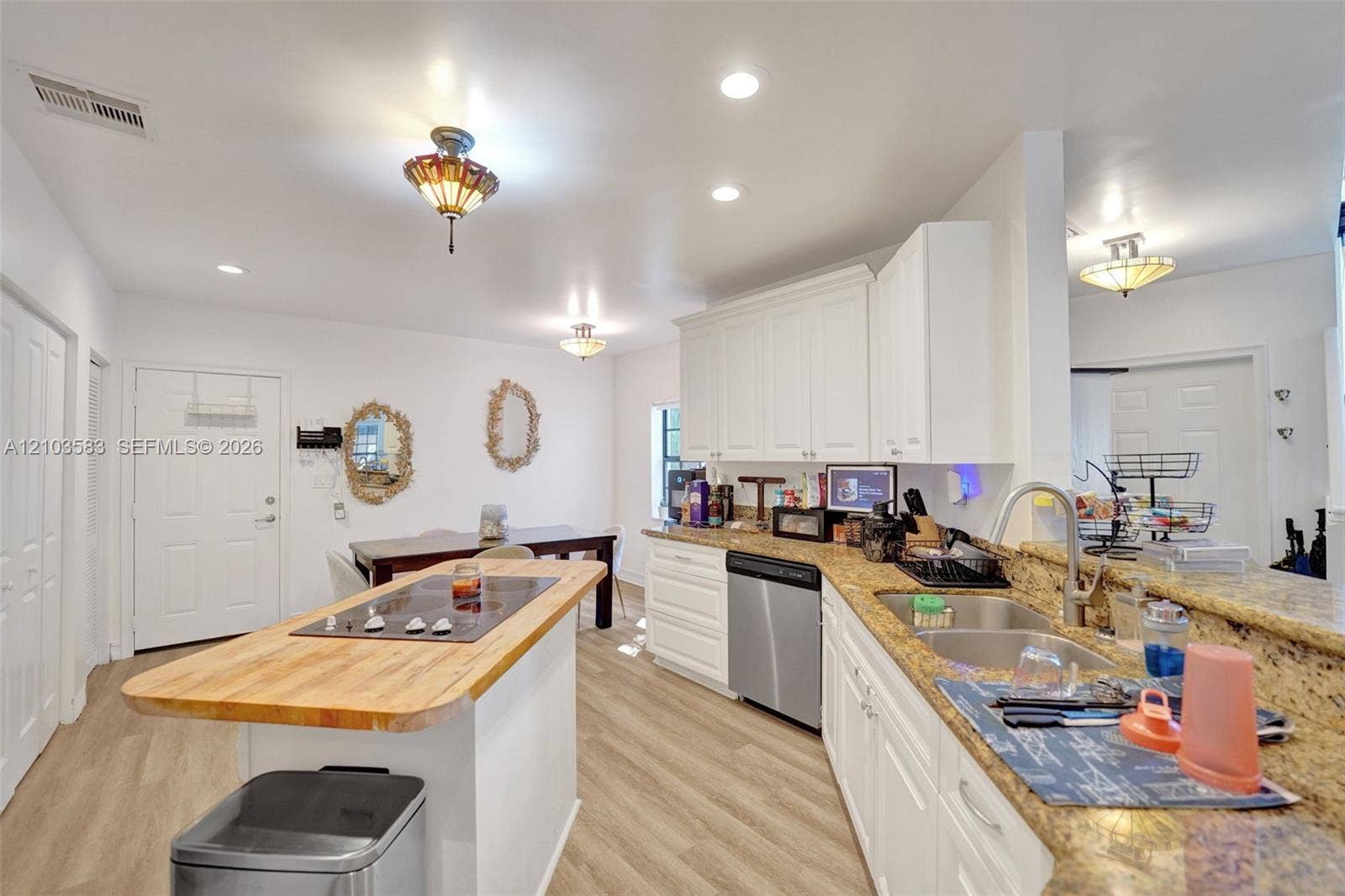 Kitchen featuring white cabinetry, stone-finish countertops, wood-finish flooring, central island with a wood-top surface, and stainless-steel appliances