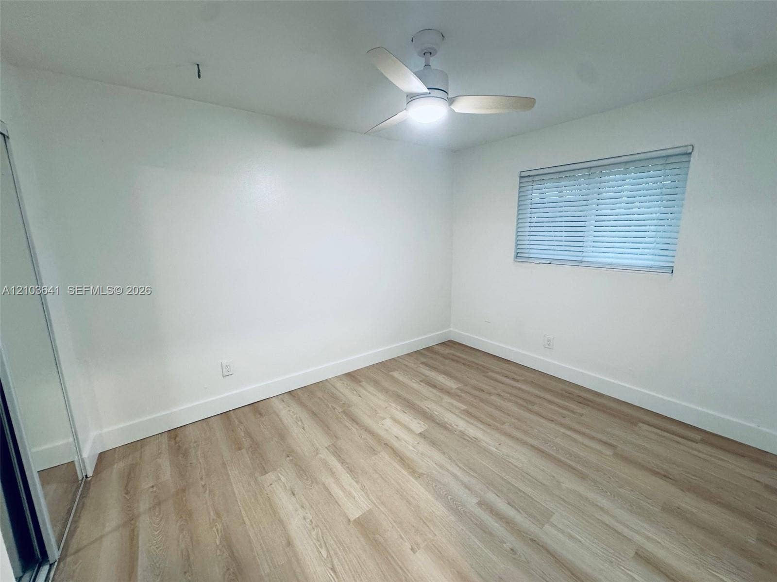 Interior room featuring wood-finish flooring, a ceiling fan with integrated lighting, and horizontal window blinds