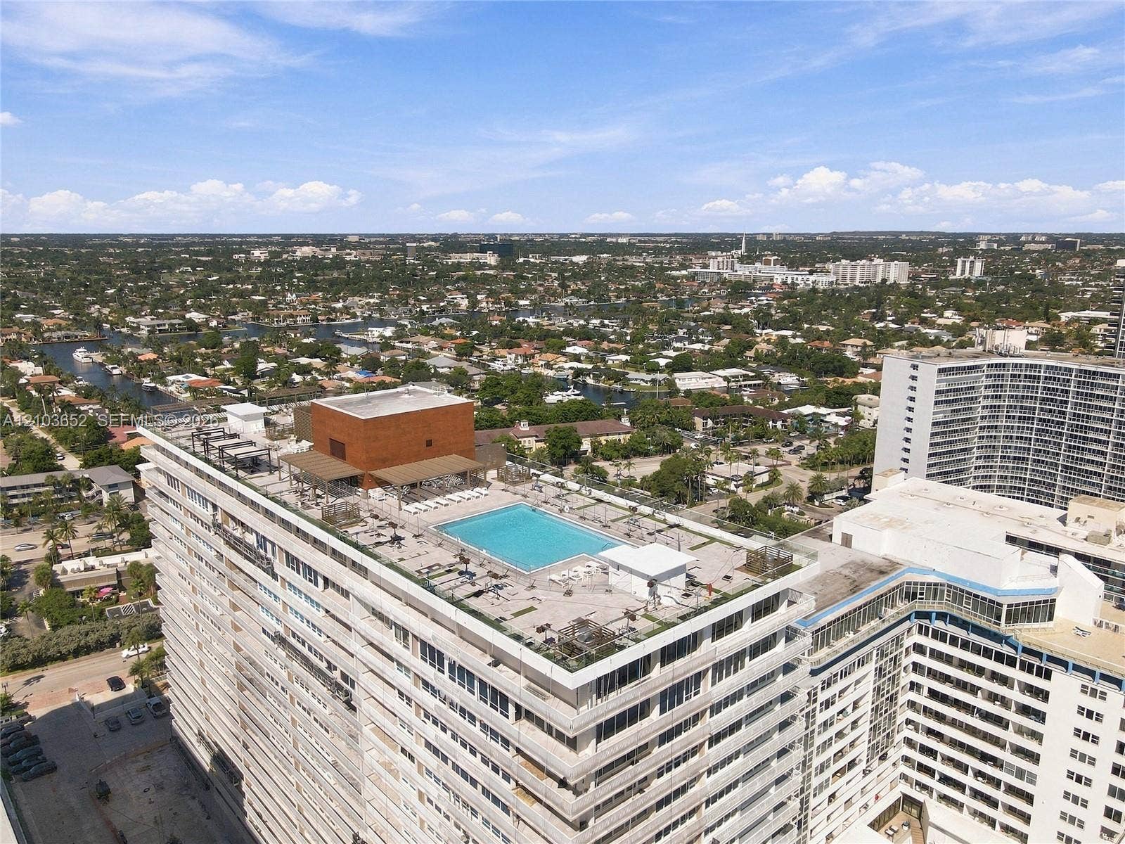 Rooftop terrace featuring a swimming pool, shaded pergola structure, and glass perimeter railings
