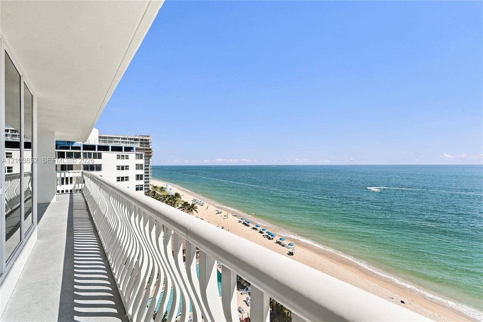 Private balcony featuring a white aluminum railing, concrete flooring, and direct oceanfront exposure