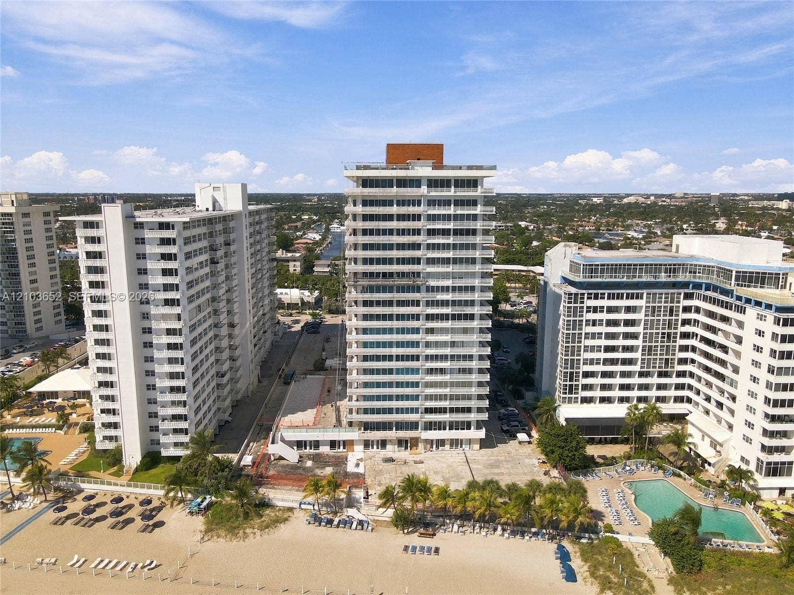 High-rise residential building featuring expansive glass balcony railings, a flat roofline, and direct sandy beach access