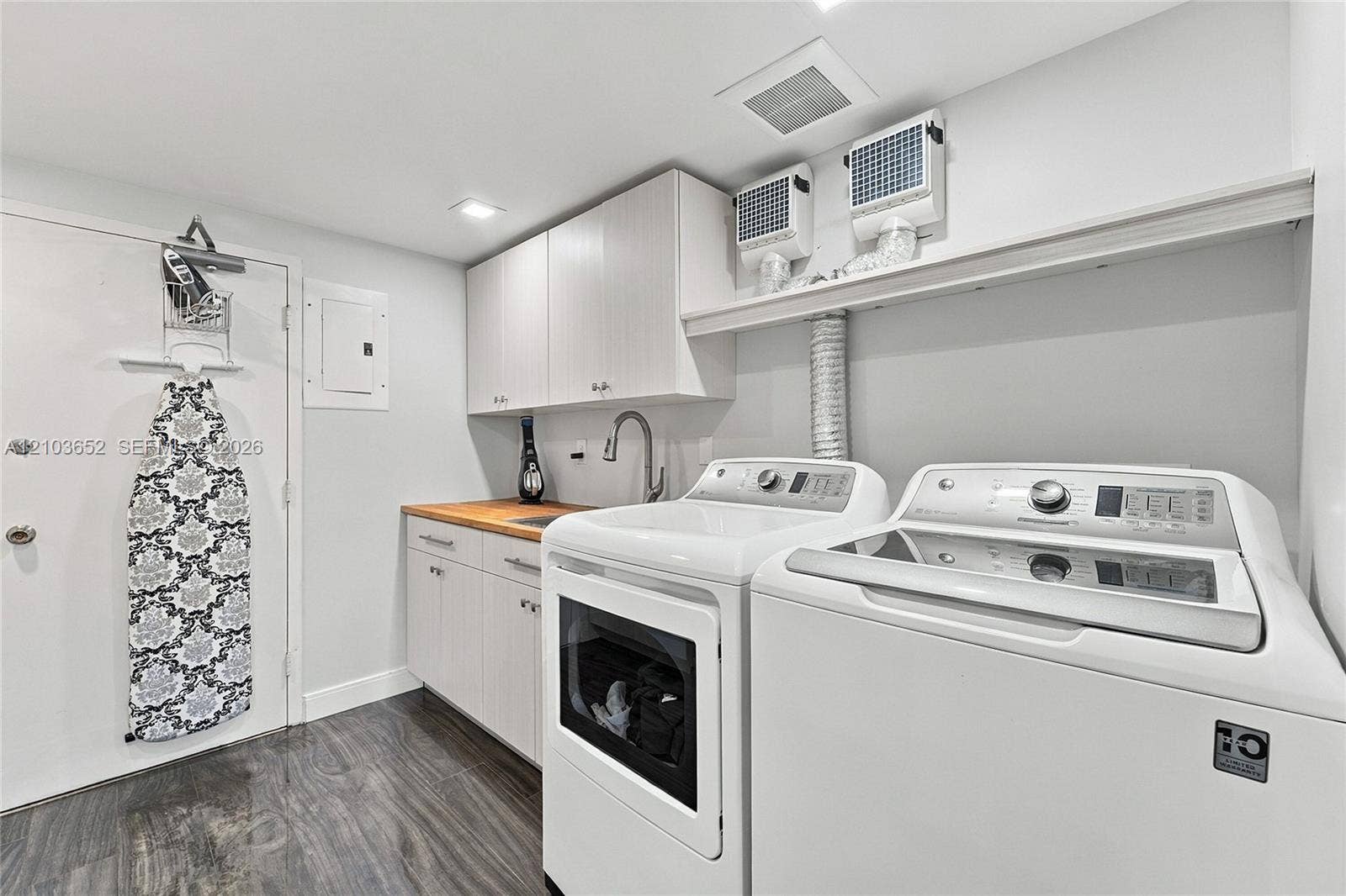 Laundry area featuring built-in cabinetry, a wood-finish countertop, a drop-in sink with a gooseneck faucet, and wood-finish flooring