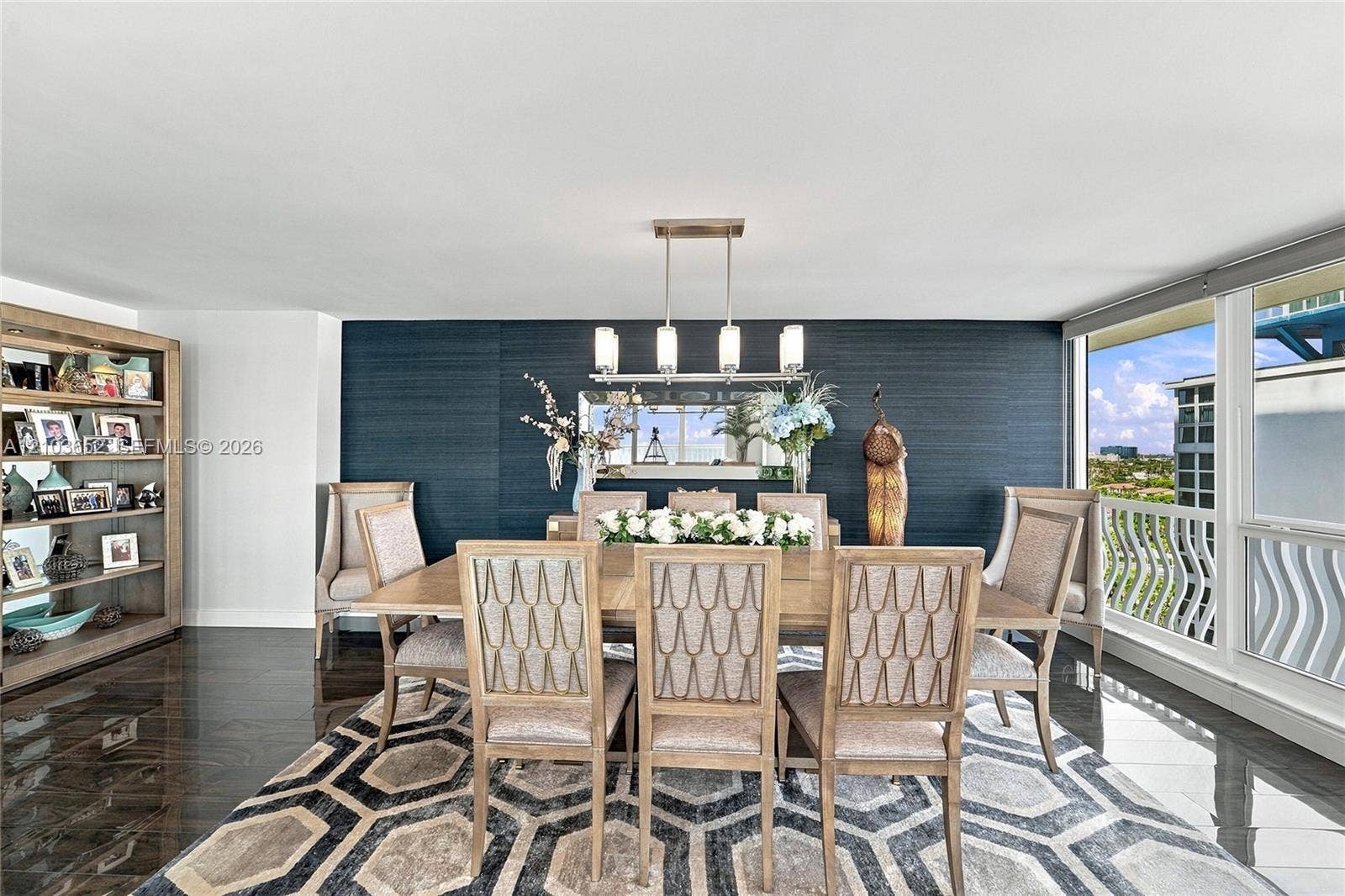 Dining area featuring dark textured wall treatment, large-format polished flooring, built-in shelving unit, linear pendant lighting, and floor-to-ceiling windows