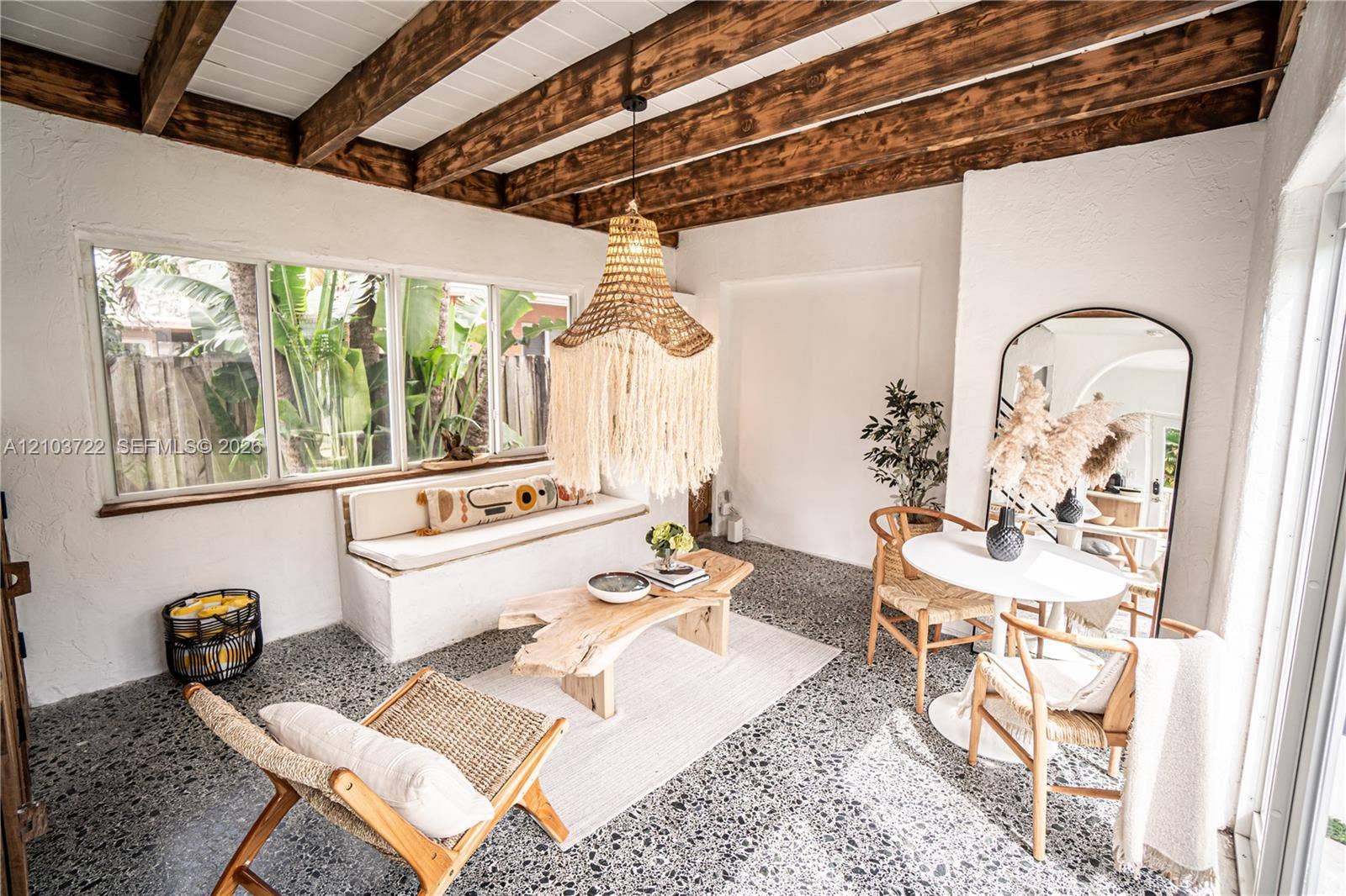 Exposed wood-beam ceiling with white planking, large picture windows, built-in masonry seating, and aggregate flooring