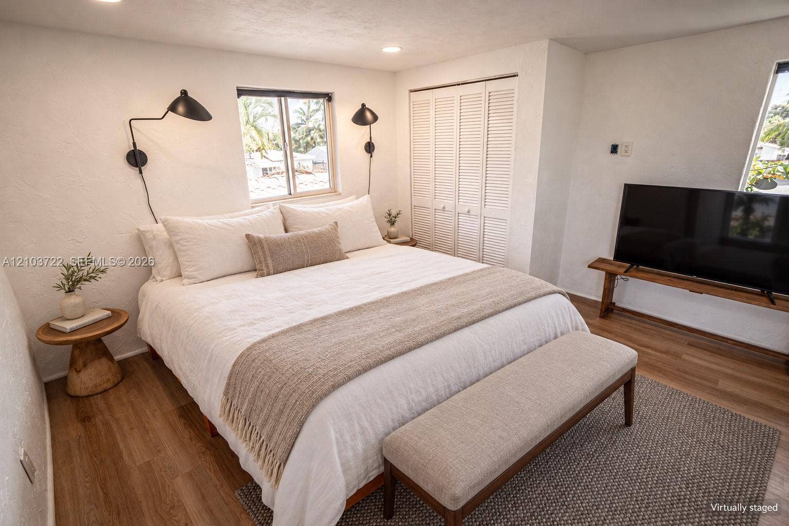 Wood-finish flooring, white walls, louvered-door closet, dual wall-mounted matte black swing-arm lamps, and recessed lighting
