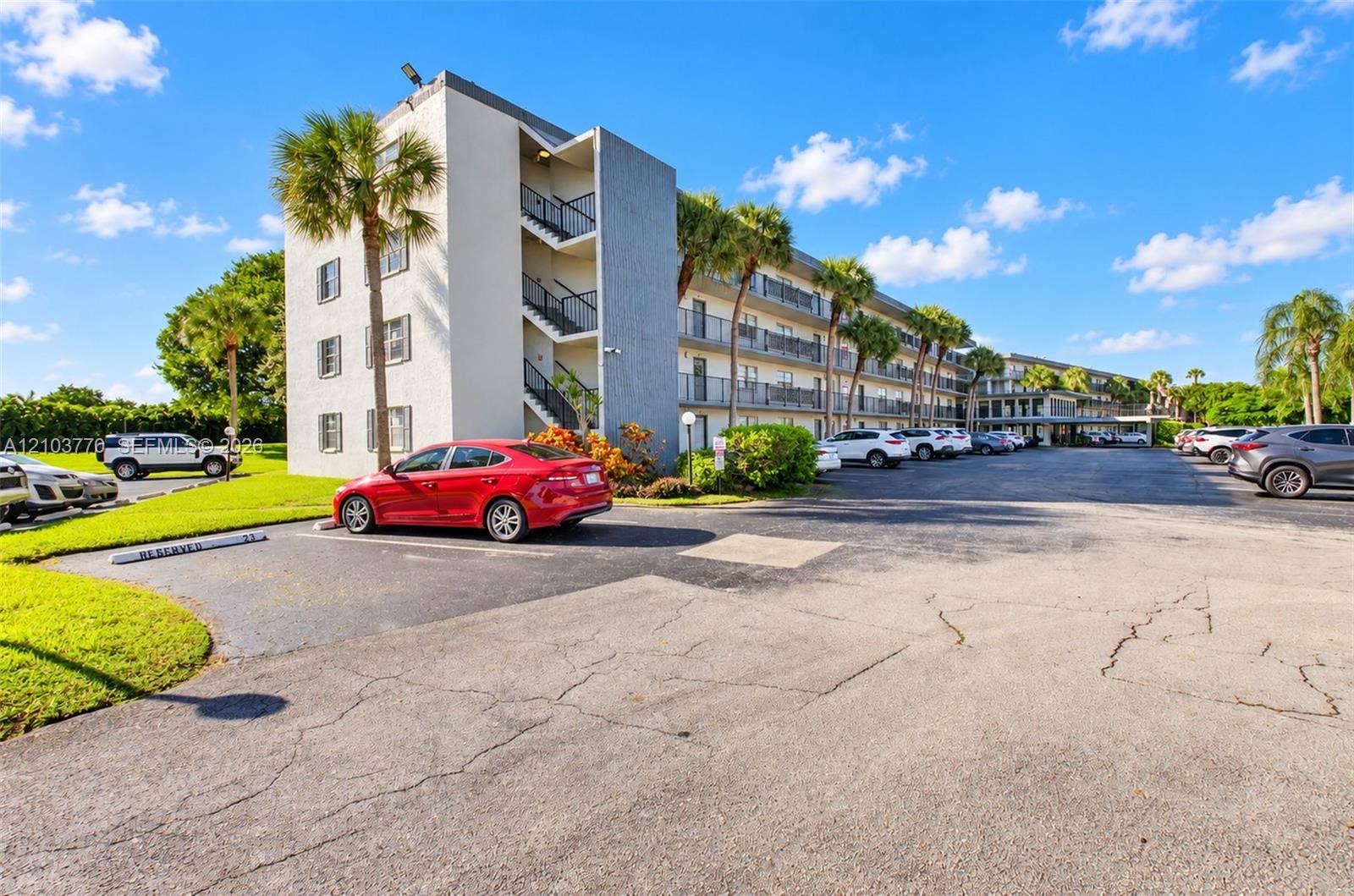 9440 SW 8th Street, #309, Boca Raton, Boca Raton, FL 33428 Multi-story building featuring exterior balconies, mature palm trees, and a paved parking area