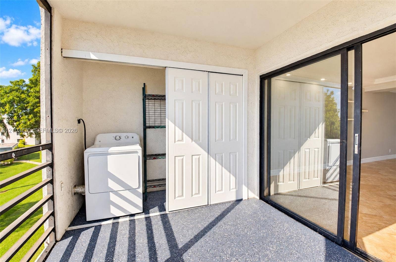 9440 SW 8th Street, #309, Boca Raton, Boca Raton, FL 33428 Balcony featuring a textured floor, sliding glass doors, and a laundry area with a dryer and shelving