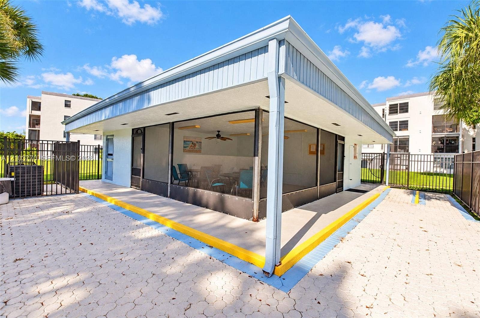 9440 SW 8th Street, #309, Boca Raton, Boca Raton, FL 33428 Enclosed structure featuring large window panels and a light-colored exterior, surrounded by a paved patio with a metal fence