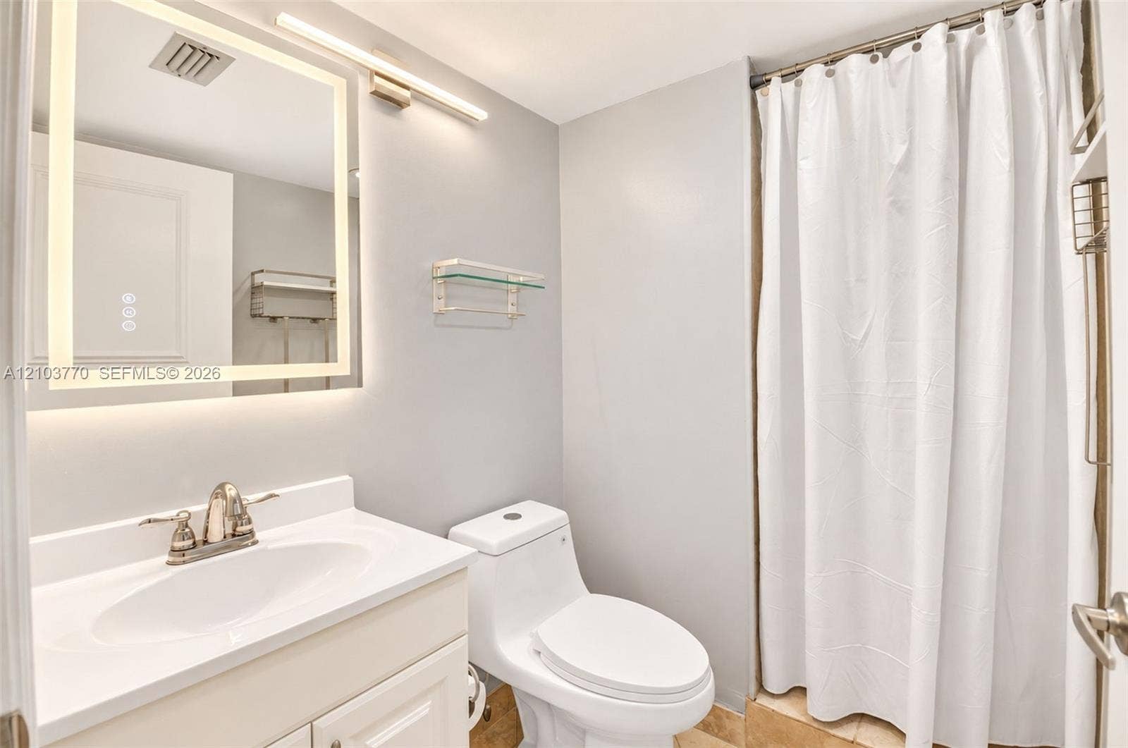 9440 SW 8th Street, #309, Boca Raton, Boca Raton, FL 33428 Illuminated mirror with integrated lighting, single vanity with a white countertop and basin, chrome-finish faucet, and a toilet with a white tank and bowl