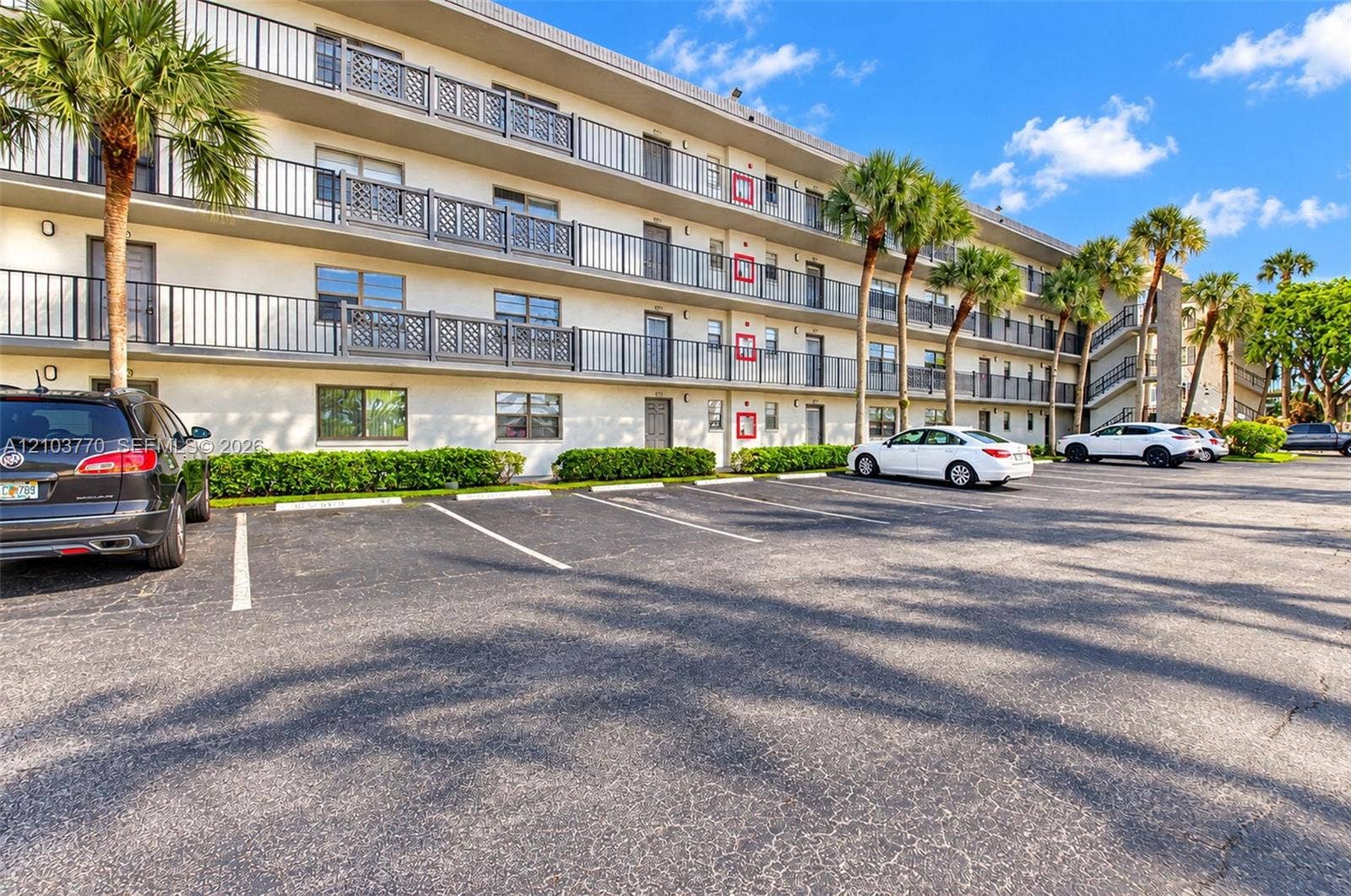 9440 SW 8th Street, #309, Boca Raton, Boca Raton, FL 33428 Multi-story building featuring balconies with black railings, a paved parking area, and manicured landscaping