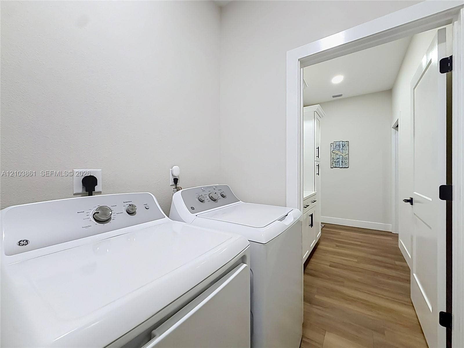 Laundry room featuring wood-finish flooring, white cabinetry, and recessed lighting