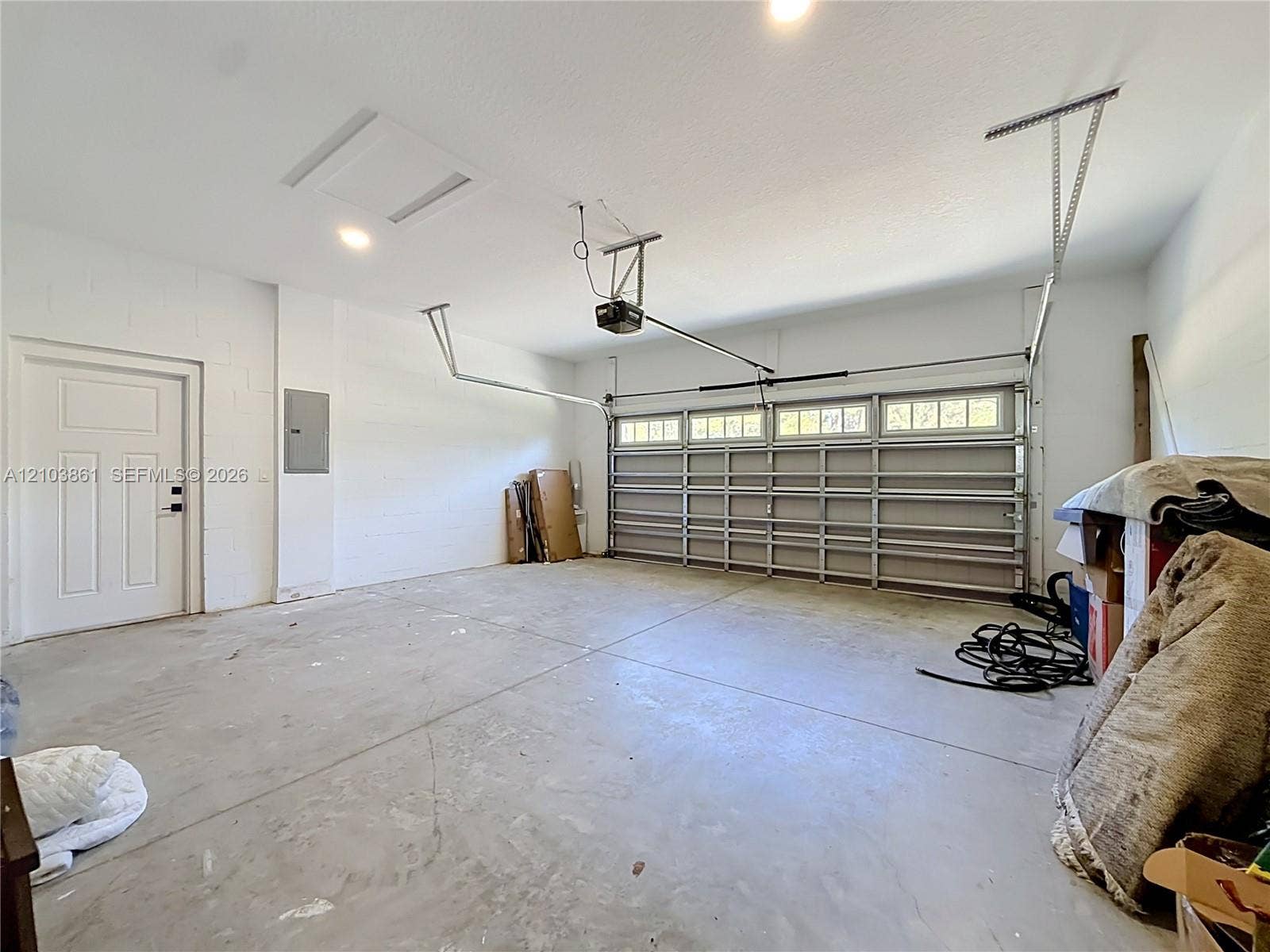 Attached two-car garage featuring a sectional door with windows, concrete flooring, painted masonry walls, and a dedicated service door