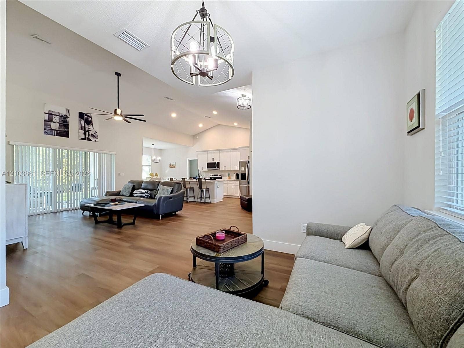 Vaulted ceilings, wood-finish flooring, metal drum pendant lighting, recessed lighting, and white cabinetry