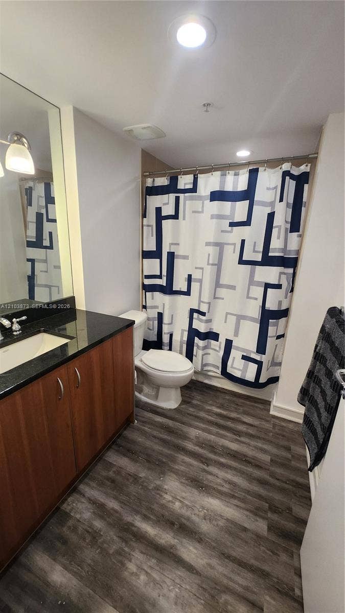 300 S Biscayne Boulevard, #L-808, Miami, FL 33131 Bathroom featuring a dark stone countertop, integrated sink, wood-finish cabinetry, recessed ceiling lighting, and wood-finish flooring