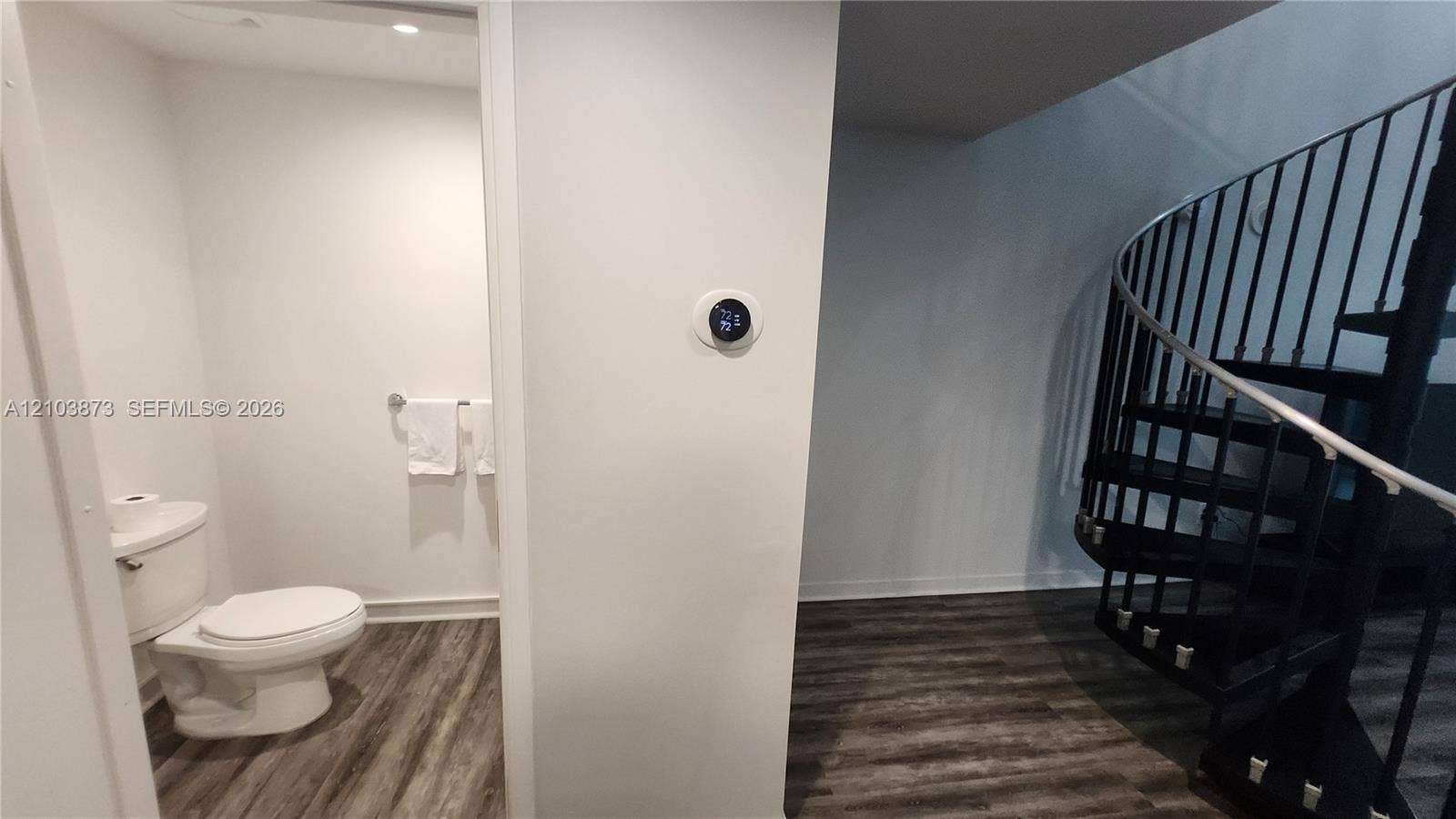 300 S Biscayne Boulevard, #L-808, Miami, FL 33131 Black metal spiral staircase featuring open risers, wood-finish flooring, smart thermostat, and a porcelain toilet