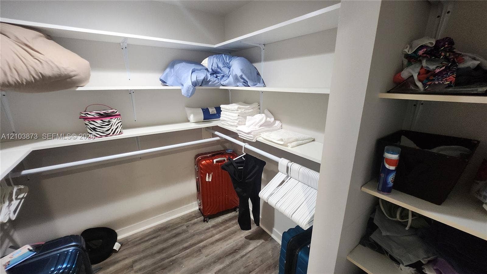 300 S Biscayne Boulevard, #L-808, Miami, FL 33131 Walk-in storage featuring tiered white shelving and a metal hanging rod over wood-finish flooring