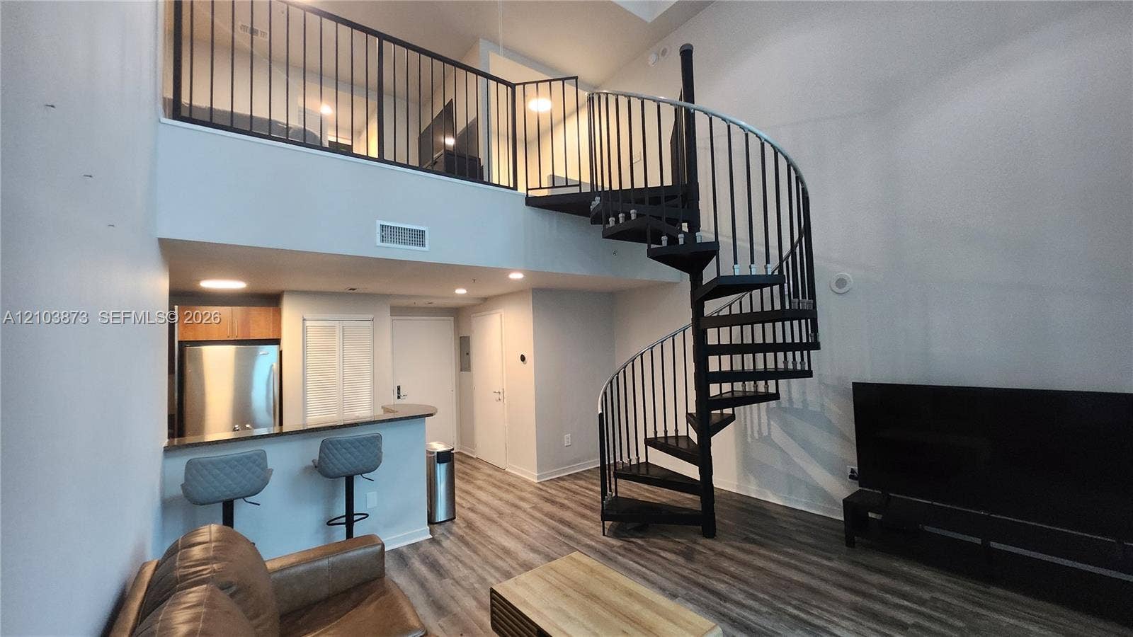 300 S Biscayne Boulevard, #L-808, Miami, FL 33131 Spiral staircase with black metal railing, wood-finish flooring, built-in breakfast bar, and mezzanine level with matching iron railing