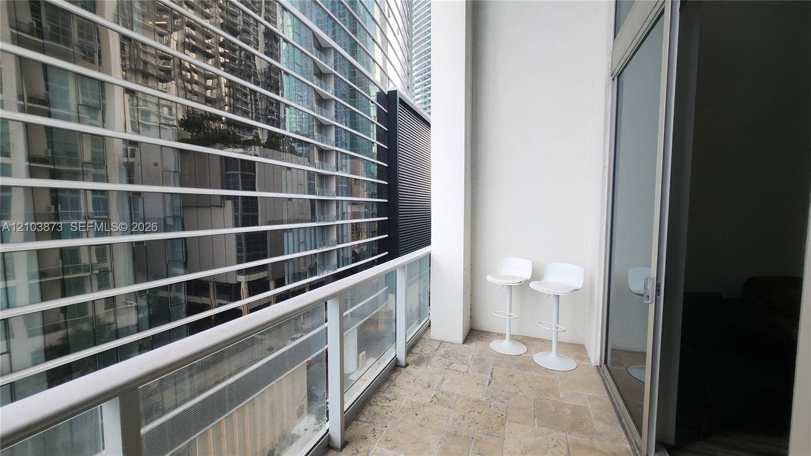 300 S Biscayne Boulevard, #L-808, Miami, FL 33131 Private covered balcony featuring stone flooring, a glass panel railing, and metal horizontal louvers