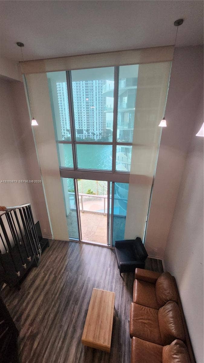 300 S Biscayne Boulevard, #L-808, Miami, FL 33131 Double-height floor-to-ceiling windows, wood-finish flooring, metal staircase railing, and pendant lighting
