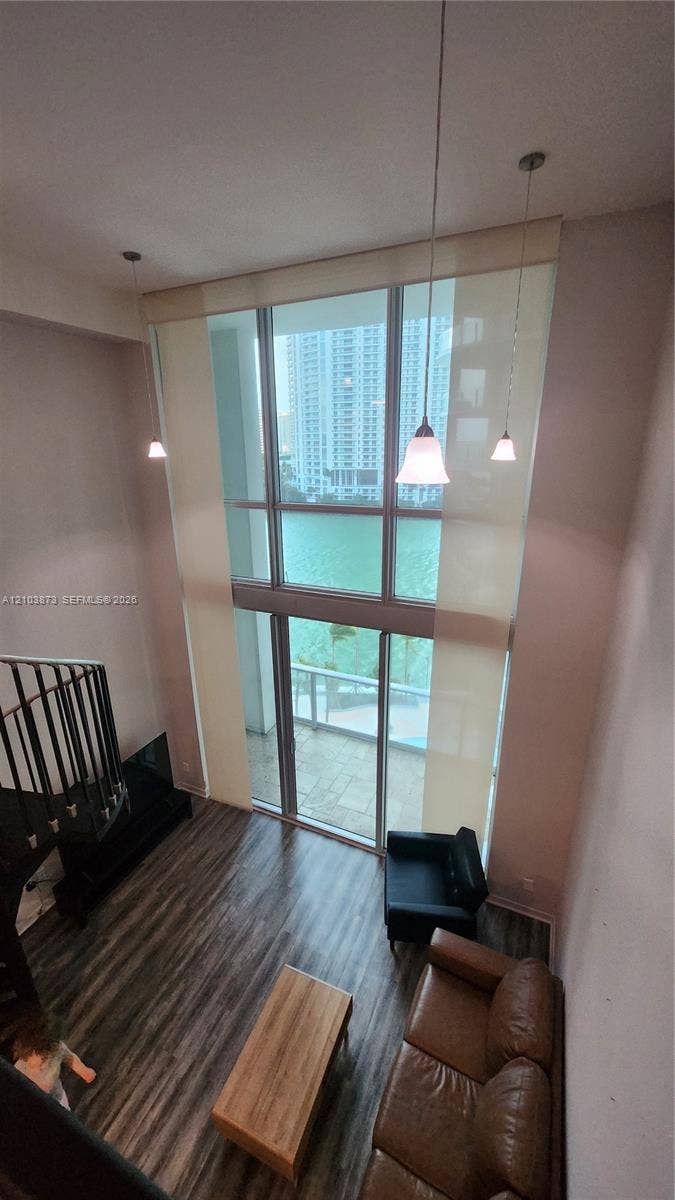 300 S Biscayne Boulevard, #L-808, Miami, FL 33131 Double-height windows with floor-to-ceiling glass, wood-finish flooring, metal spiral staircase, and three pendant light fixtures