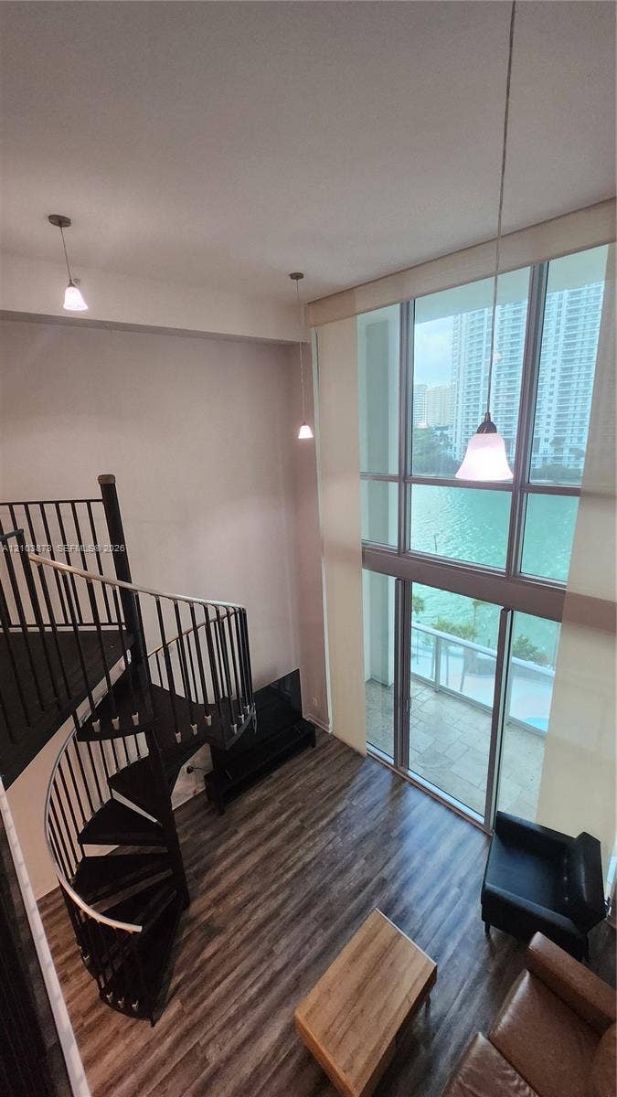 300 S Biscayne Boulevard, #L-808, Miami, FL 33131 Double-height floor-to-ceiling windows, spiral staircase with metal railings, wood-finish flooring, and pendant lighting