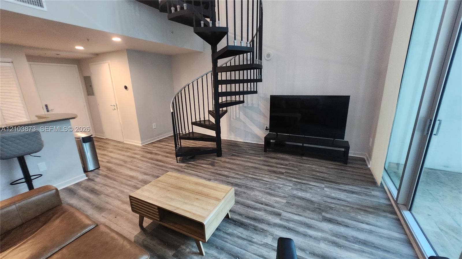 300 S Biscayne Boulevard, #L-808, Miami, FL 33131 Open-concept interior featuring wood-finish flooring, a black metal spiral staircase, recessed lighting, and a floor-to-ceiling glass sliding door
