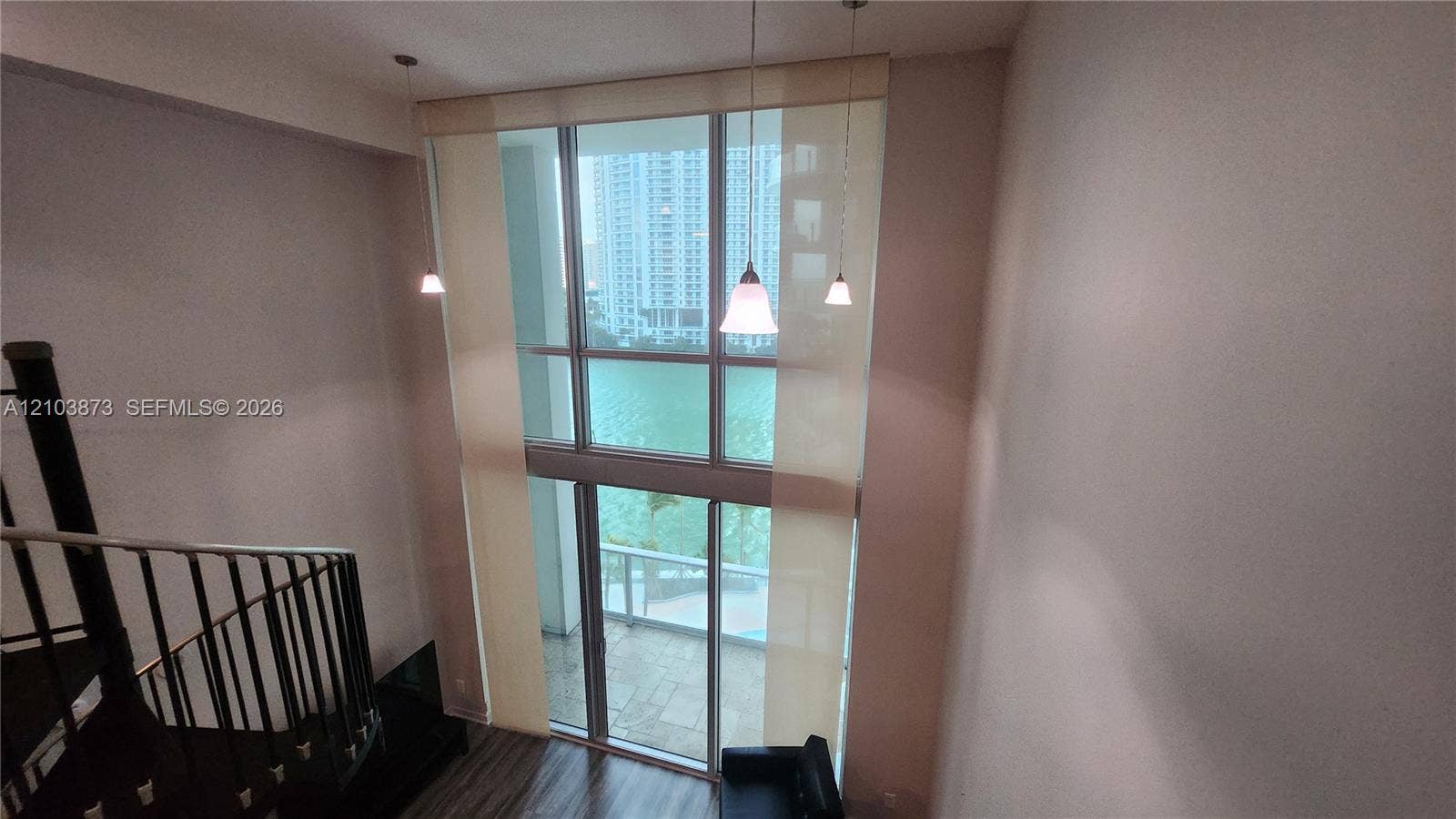 300 S Biscayne Boulevard, #L-808, Miami, FL 33131 Double-height floor-to-ceiling windows, suspended pendant lighting, dark metal spiral staircase with railing, and wood-finish flooring