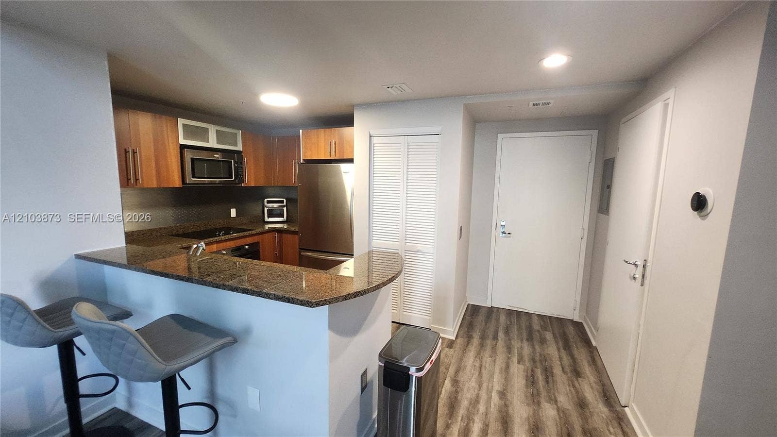 300 S Biscayne Boulevard, #L-808, Miami, FL 33131 Kitchen featuring wood-finish cabinetry, stone-surface breakfast bar, stainless steel refrigerator, built-in microwave, and wood-finish flooring