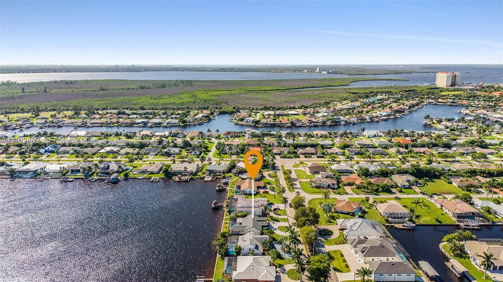 Aerial perspective of waterfront property featuring direct canal access, a concrete seawall, and proximity to open water